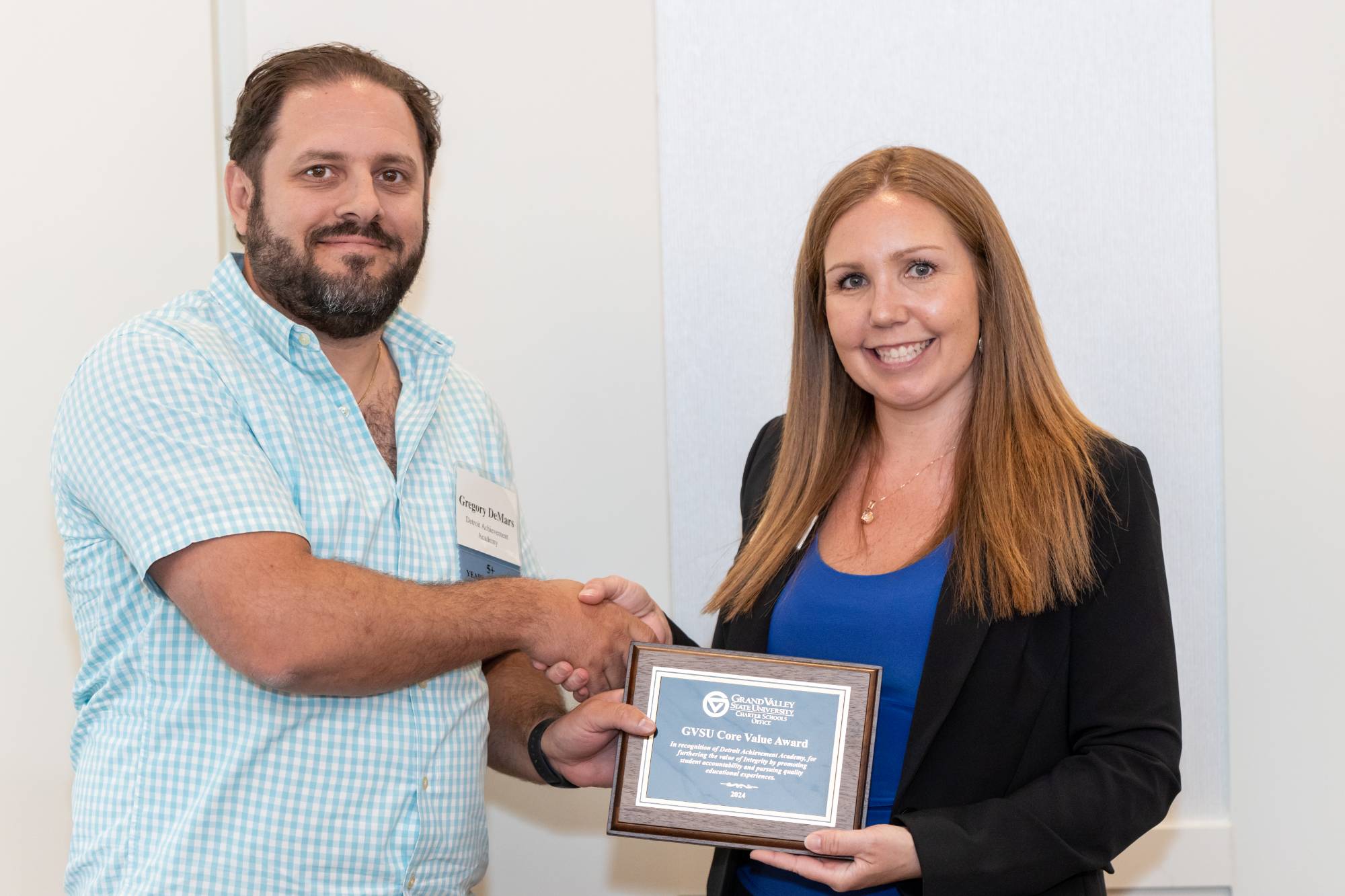 A board member from Detroit Achievement Academy accepting the award from Gretchen Lahaie